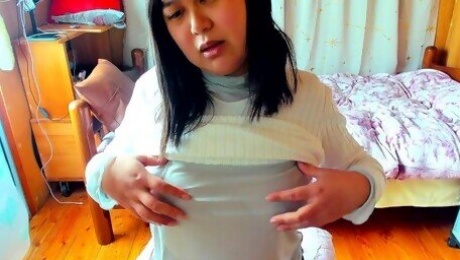 A busty Japanese woman enjoys masturbating her nipples through her see-through top.